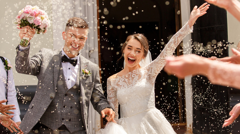 Bride and groom leaving wedding amidst rice 