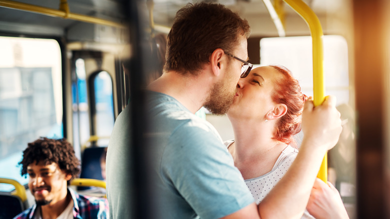 Man and woman kissing on a public bus during the day